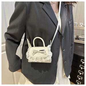 Gros plan détaillé du mini sac à main blanc avec dentelle et nœud, porté en bandoulière