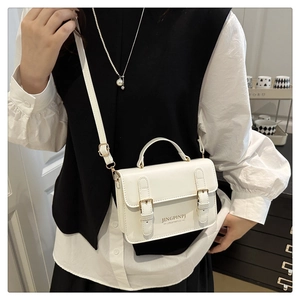 Detalle de mini bolso bandolera de cuero blanco con hebillas decorativas y correa ajustable