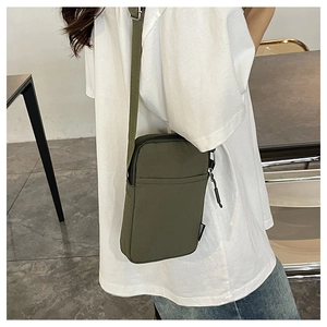 Detail of army green nylon crossbody phone bag featuring fashion label and adjustable strap