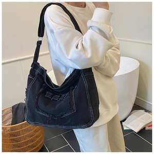 Detail van zwarte denim shopper met witte contraststiksels en gerafelde vintage randen