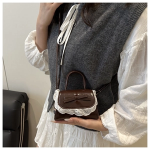Détail d'un mini sac à main en cuir marron avec dentelle blanche et nœud porté par un mannequin
