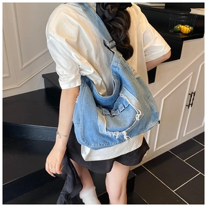 Foto lifestyle della grande borsa hobo in denim azzurro con bordi sfrangiati