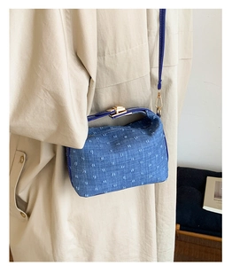 Detail der blauen Denim-Umhängetasche mit weißen Punkten und goldenem Metallschloss