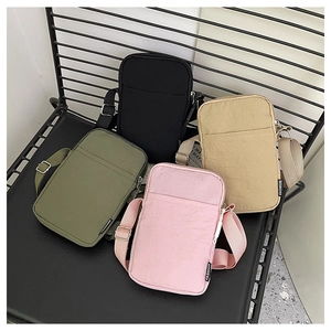 Detail of four colorful nylon crossbody mini bags with fashion tags on a grid chair