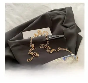 Detail of floral embroidery and shiny sequins on a chain bag over a black blazer