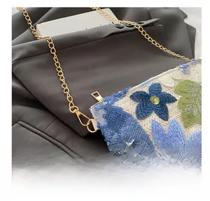 Detailed shot of floral sequin embroidery and gold chain strap on woven clutch bag