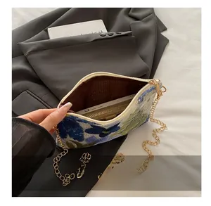 Detail view of woven sequin clutch interior with chain strap and embroidered floral patterns