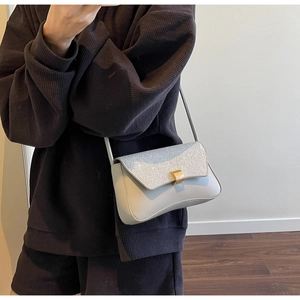Détail du sac baguette en cuir gris avec rabat pailleté argenté et fermoir doré