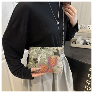 Detail of embroidered sequin shoulder bag with intricate leaf patterns and gold chain
