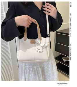 Detail of white leather tote bag with rabbit charm and fashion embossed texture