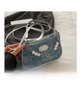Detail of blue glitter denim shoulder bag featuring pearl and silver flower chain