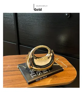 Détail du sac de soirée croissant fini miroir doré avec fine chaîne sur bureau noir
