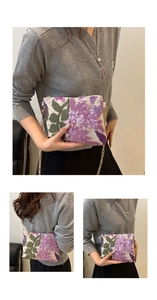 Detailed close-up of sequin floral embroidery and gold chain strap on the white clutch bag