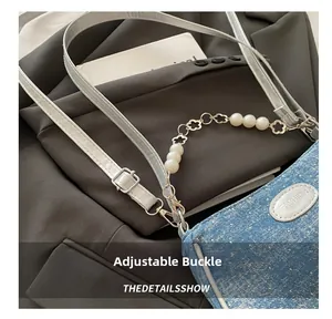 Detail of denim crossbody bag featuring pearl flower chain and adjustable buckle strap