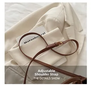 Gros plan sur la bandoulière en cuir marron avec boucle dorée réglable d'un sac chic