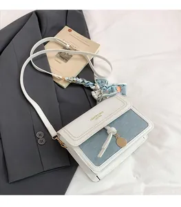 Détail d'un sac bandoulière carré avec poignée en foulard de soie et pendentif
