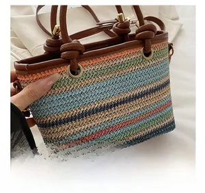 Détail du tressage en paille multicolore et de la poignée en cuir marron sur un sac seau