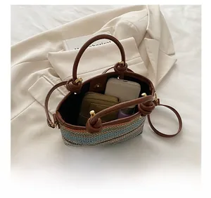 Vue détaillée de la capacité d'un sac en paille rayé contenant téléphone et portefeuille