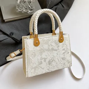 Nahaufnahme der cremefarbenen Jacquard-Handtasche mit floraler Spitze und Webgriffen