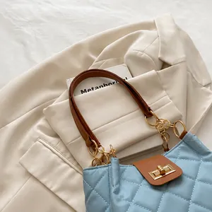 Detalle de bolso acolchado azul claro con cadena dorada, cierre de giro y asa cuero