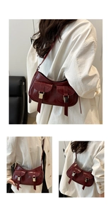 Detail view of burgundy crescent shoulder bag with twin front pockets and silver buckles