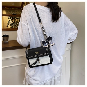 Détail du sac bandoulière contrasté avec clous et foulard en soie sur la lanière