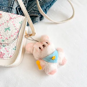 Gros plan d'un pendentif animal en peluche avec bandana bleu sur un sac à main blanc