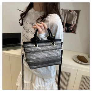 Détail d'un sac en paille tressée avec dégradé gris et poignée en cuir noir