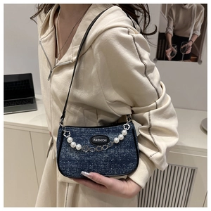 Detalle del bolso de hombro denim azul oscuro con perlas blancas y cadena floral