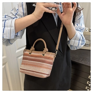 Detail of striped woven straw beach bag with round handles and leather shoulder strap
