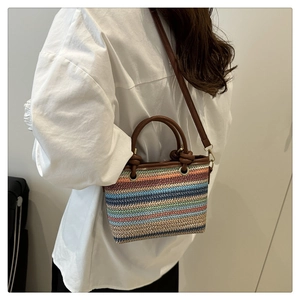 Détail du sac seau en paille tressée multicolore avec poignées et bandoulière en cuir