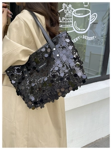 Detail of black sequin tote bag with leather strap and silver metal rivet accents