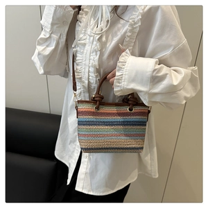 Detail of colorful striped woven straw bag with brown leather handles and adjustable strap