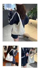 Detailed view of beige canvas tote bag with blue text worn in a cafe setting