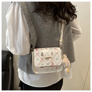 Gros plan du sac bandoulière blanc imprimé floral avec lapin en peluche et logo doré
