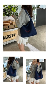 Detail of red embroidered text on a durable navy canvas tote bag for daily commute