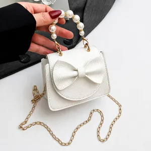 Detail der weißen Tasche aus Litschileder mit Perlengriff und schicker Schleife