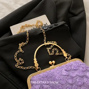 Detail der lila 3D-Blumen-Kettentasche mit goldener Ringgriff auf einem schwarzen Sakko
