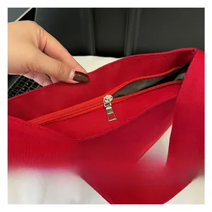 Detail of red canvas tote bag featuring smooth metal zipper and logo print detail