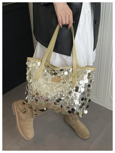 Detail of a large silver sequin tote bag with leather handles and metallic texture