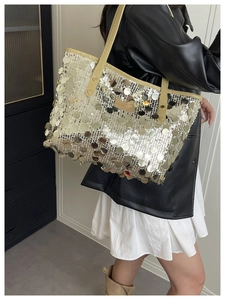 Detail of sequin tote bag with leather handles and metallic finish on shoulder
