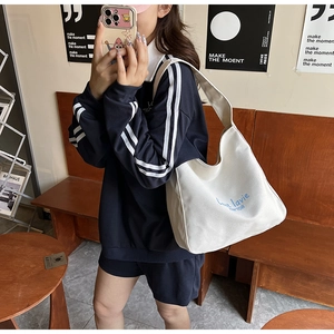 Détail d'un grand sac cabas en toile blanche avec lettrage cursif bleu C'est la vie