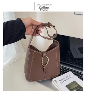 Detail of coffee brown PU leather bucket bag featuring white contrast stitching and gold ring