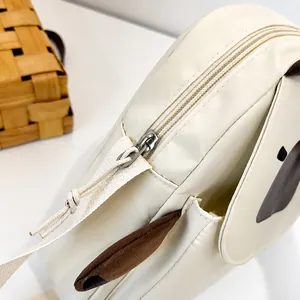 Close-up of the smooth metal zipper design on a beige nylon shoulder bag with details