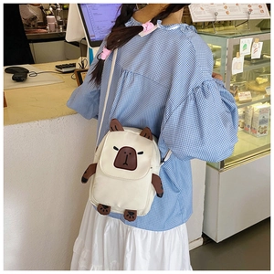 Detail of cute embroidered capybara cartoon crossbody bag with 3D ears on a beige fabric