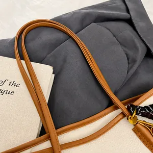 Close-up of gray tote bag with brown leather strap and Eiffel Tower charm detail
