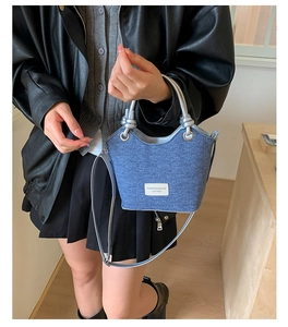 Dettaglio borsa hobo in denim blu con manico in metallo argento e tracolla fine