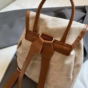 Detailed view of canvas backpack back with brown leather straps and metal hardware
