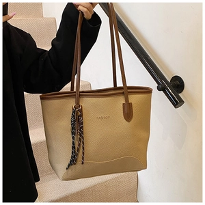 Detail of beige lychee texture leather tote with brown strap and fashion embossing