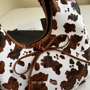 Detailaufnahme der Cow-Print-Tasche mit brauner Lederschleife und Nahtkanten